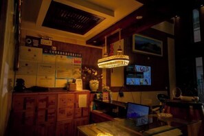 A dimly lit room with wooden cabinets, a desk with a computer, and a television mounted on the wall. - Boao Yingke Hotel (Dali City)