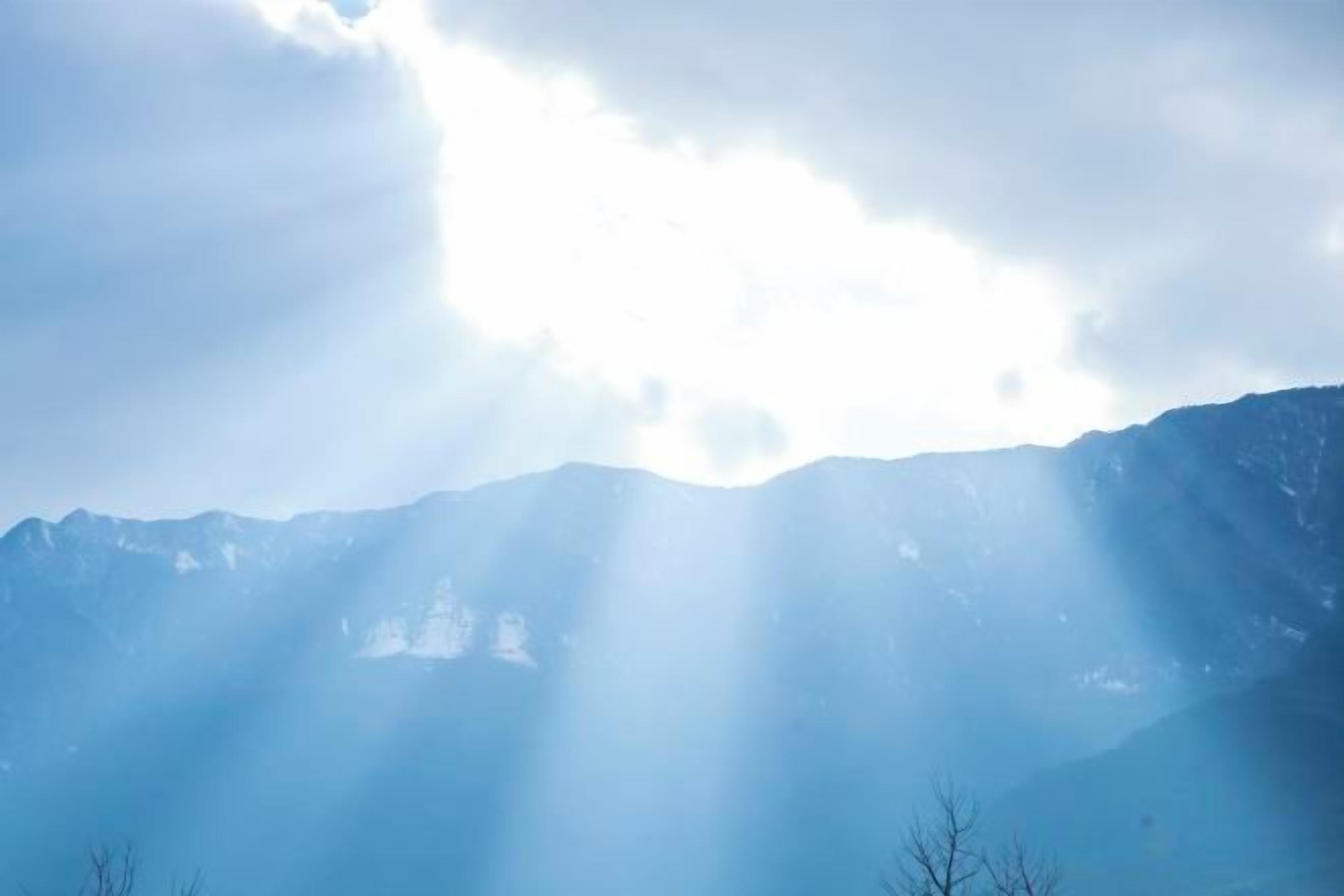 A mountain range with sunlight filtering through clouds.