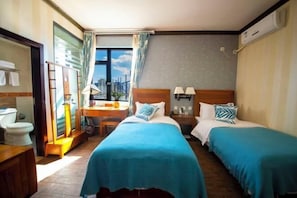 A hotel room with two beds, a desk, a chair, a window with curtains, and a view of the city. - Boao Yingke Hotel (Dali City)