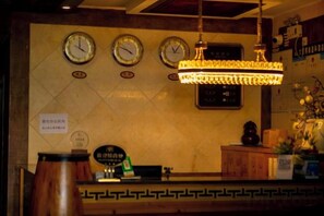 A reception area with a counter, clocks, and a chandelier. - Boao Yingke Hotel (Dali City)