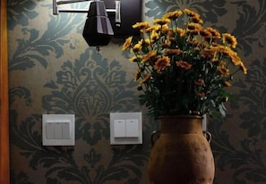 A room with a patterned wallpaper, a vase with yellow flowers, and two wall-mounted light switches. - Boao Yingke Hotel (Dali City)