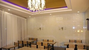 A dining area with wooden tables and chairs, a chandelier, and a tiled wall. - Lumingchun Hotel (Changbai Mountain North Scenic Area Distribution Center) (Antu)