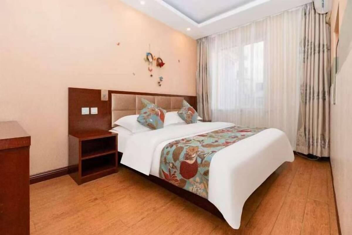 A neatly arranged hotel room with a large bed, a bedside table, and a small shelf unit.