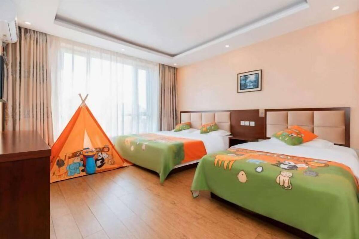 A hotel room with two beds, a tent, and a large window.
