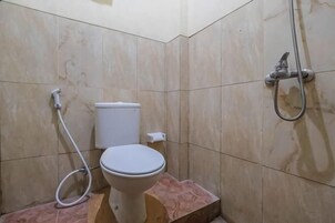A bathroom with a toilet, a shower, and a marble-tiled wall.