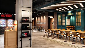A modern restaurant with a long wooden table and chairs, a self-ticket machine, and a wall with a motivational quote. - Vinhomes Central Park - The Landmark (Ho Chi Minh City)
