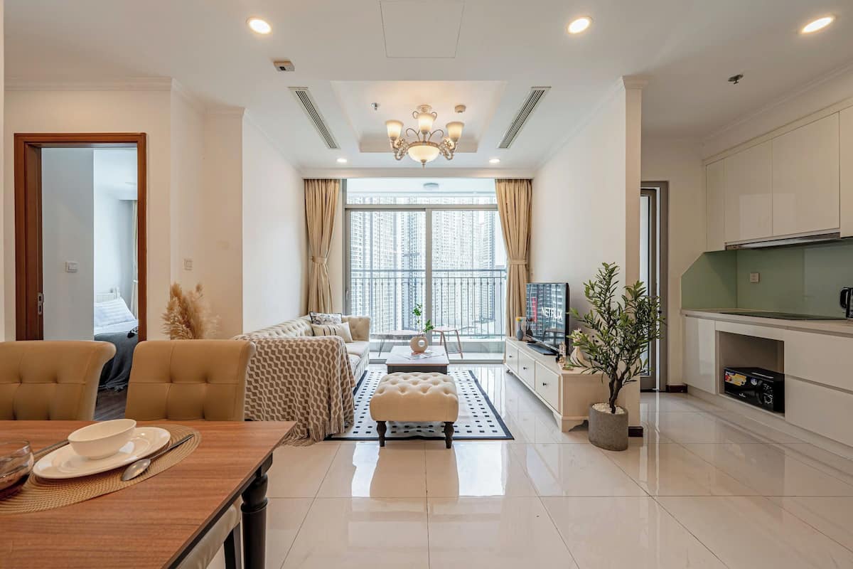 A modern living room with a sofa, dining table, and a kitchen area with cabinets and a TV.
