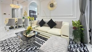 A modern living room with a white sofa, black and white patterned rug, and a chandelier. - Vinhomes Central Park - The Landmark (Ho Chi Minh City)