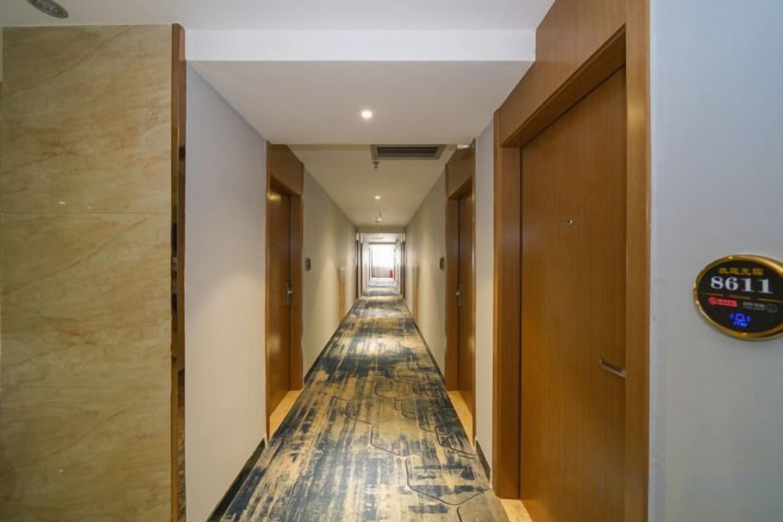 A corridor with a patterned carpet, wooden doors, and a sign indicating room number 8611.
