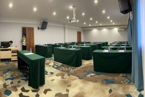 Une salle de conférence équipée de plusieurs tables, d’un projecteur et d’un écran de télévision.