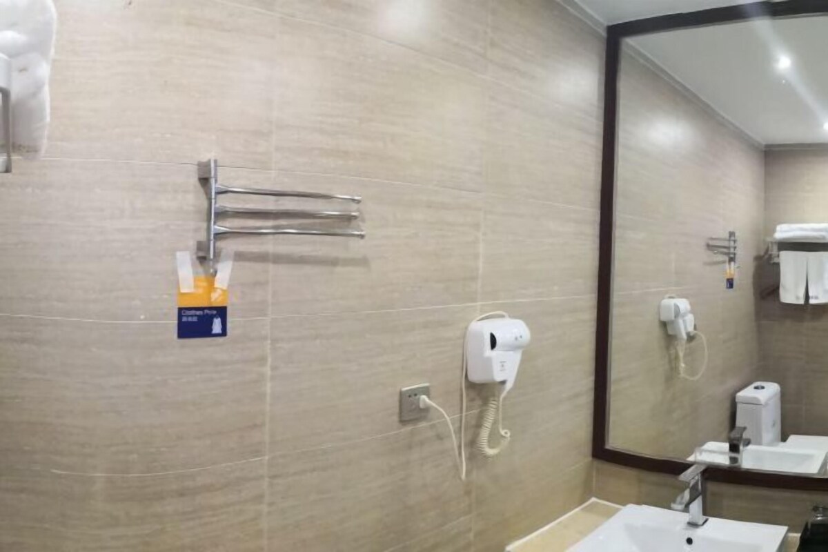Casa de banho com lavatório, espelho, porta-toalhas e secador de mãos.
