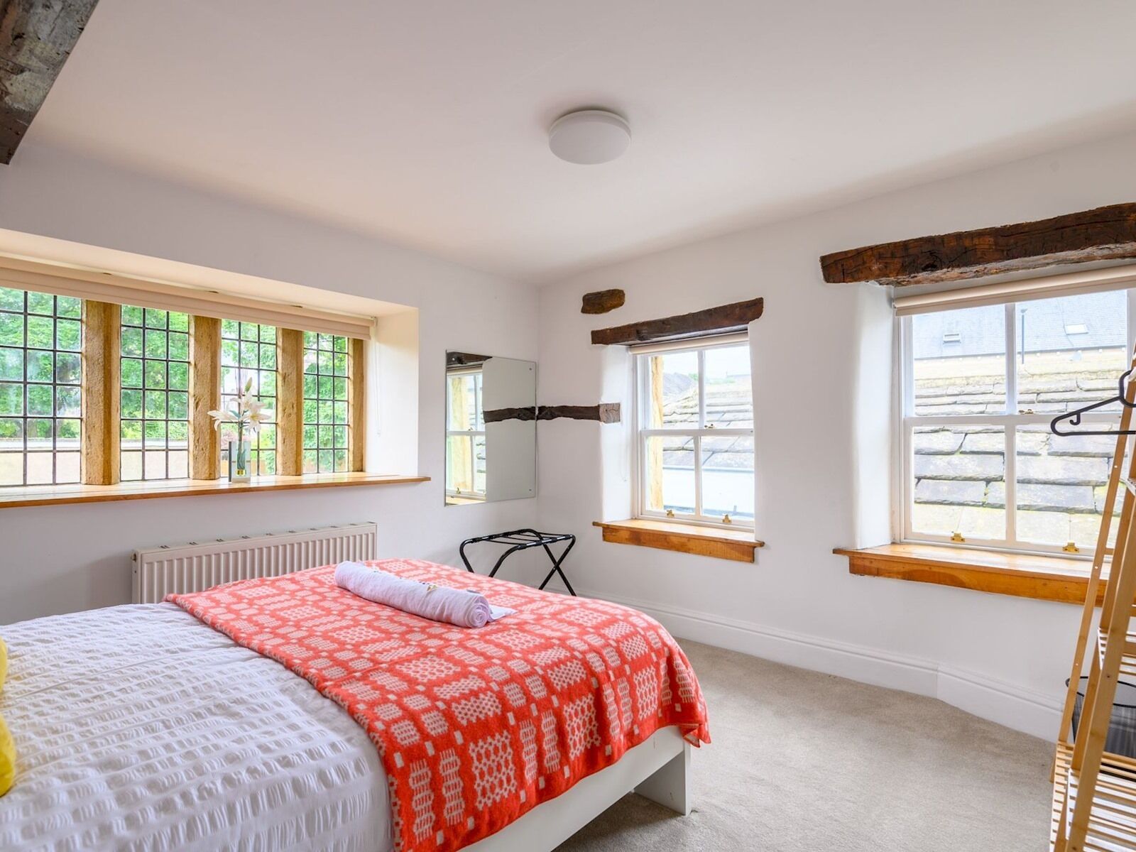 Une chambre à coucher avec un lit, un radiateur, un miroir et une fenêtre donnant sur l’extérieur.