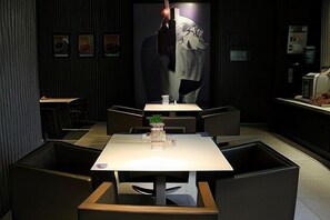 A modern restaurant with a minimalist design, featuring a central table with a vase of flowers, surrounded by dark-toned chairs. - Jinjiang inn (Shanghai Chedun Film Shooting Base) (Shanghai)