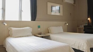 A hotel room with two single beds, a bedside table with a lamp, a small desk with a chair, and a window with curtains. - Jinjiang inn (Shanghai Chedun Film Shooting Base) (Shanghai)