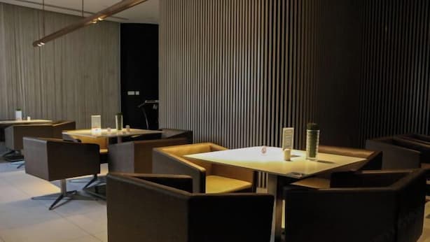A modern restaurant with dark-toned booths and rectangular tables, featuring a vertical striped wall and a wooden panel backdrop. - Jinjiang inn (Shanghai Chedun Film Shooting Base) (Shanghai)
