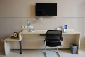 A hotel room with a desk, chair, TV, lamp, and a trash bin. - Jinjiang inn (Shanghai Chedun Film Shooting Base) (Shanghai)