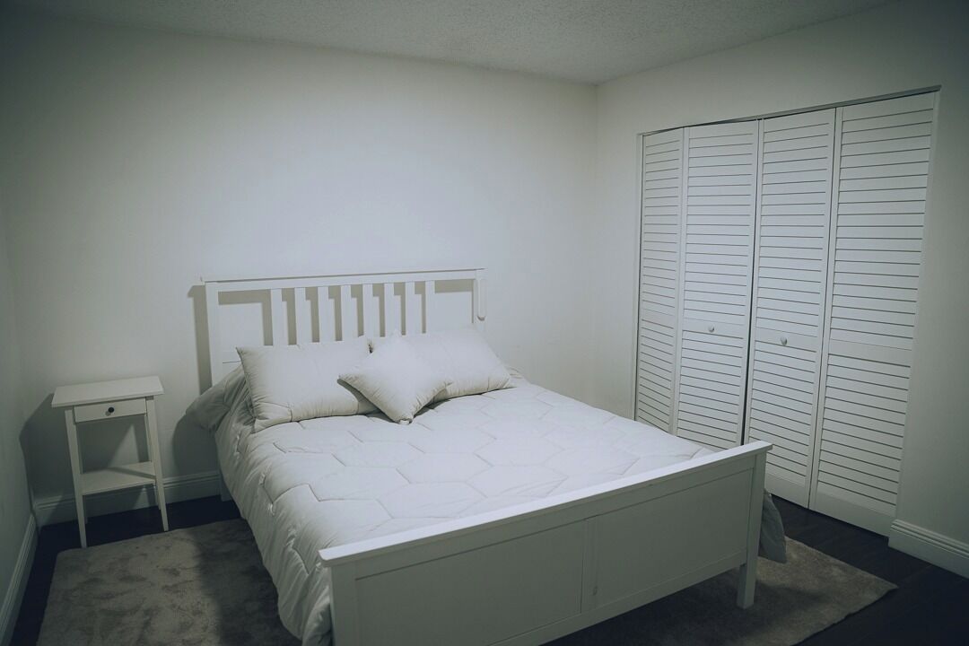 A bedroom with a bed, a nightstand, and a closet.