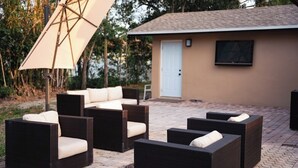 Un espace extérieur aménagé avec des meubles en osier et un grand parasol.