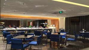 A modern restaurant with blue chairs and tables, a bar area, and a kitchen in the background. - Winterless Hotel (Beijing XiDiaoyutai Subway Station branch) (Beijing)