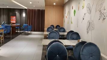 A conference room with tables and chairs, a wooden partition, and a wall with botanical illustrations.