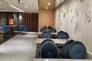 A conference room with tables and chairs, a wooden partition, and a wall with botanical illustrations.