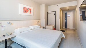 A hotel room with a bed, bedside table with a phone, a small cabinet, a framed picture on the wall, and a door leading to another room. - Winterless Hotel (Beijing XiDiaoyutai Subway Station branch) (Beijing)