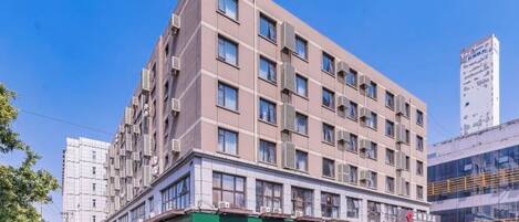 A multi-story hotel with a flat facade, large windows, and a green awning.
