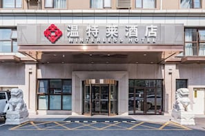 The Winterless Hotel entrance with a lion statue on either side. - Winterless Hotel (Beijing XiDiaoyutai Subway Station branch) (Beijing)
