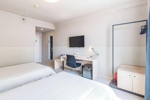 Habitació d'hotel amb dos llits, una taula de treball amb cadira, televisió i un armari.