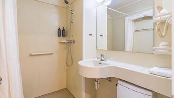 Un baño con ducha, lavamanos, espejo y perchero para toallas.