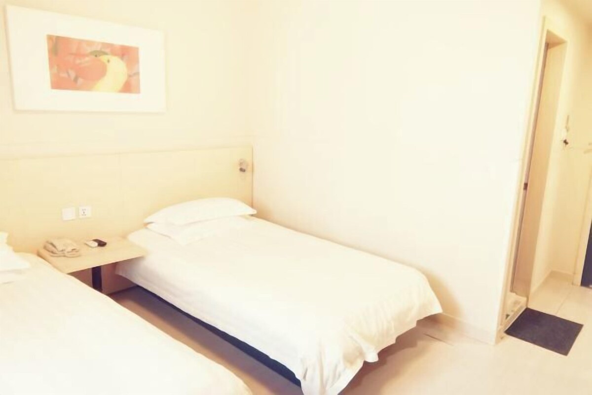 Habitació individual amb una tauleta de nit, un telèfon i un quadre al mur.