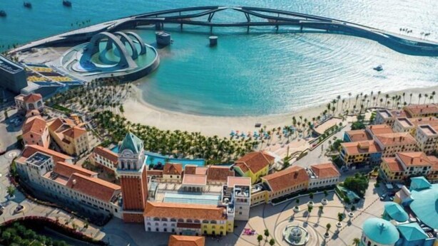 An aerial view of a coastal resort with a central plaza, a bridge, and a circular water feature. - Juliet Boutique Hotel - Sunset Town (Phu Quoc Island)