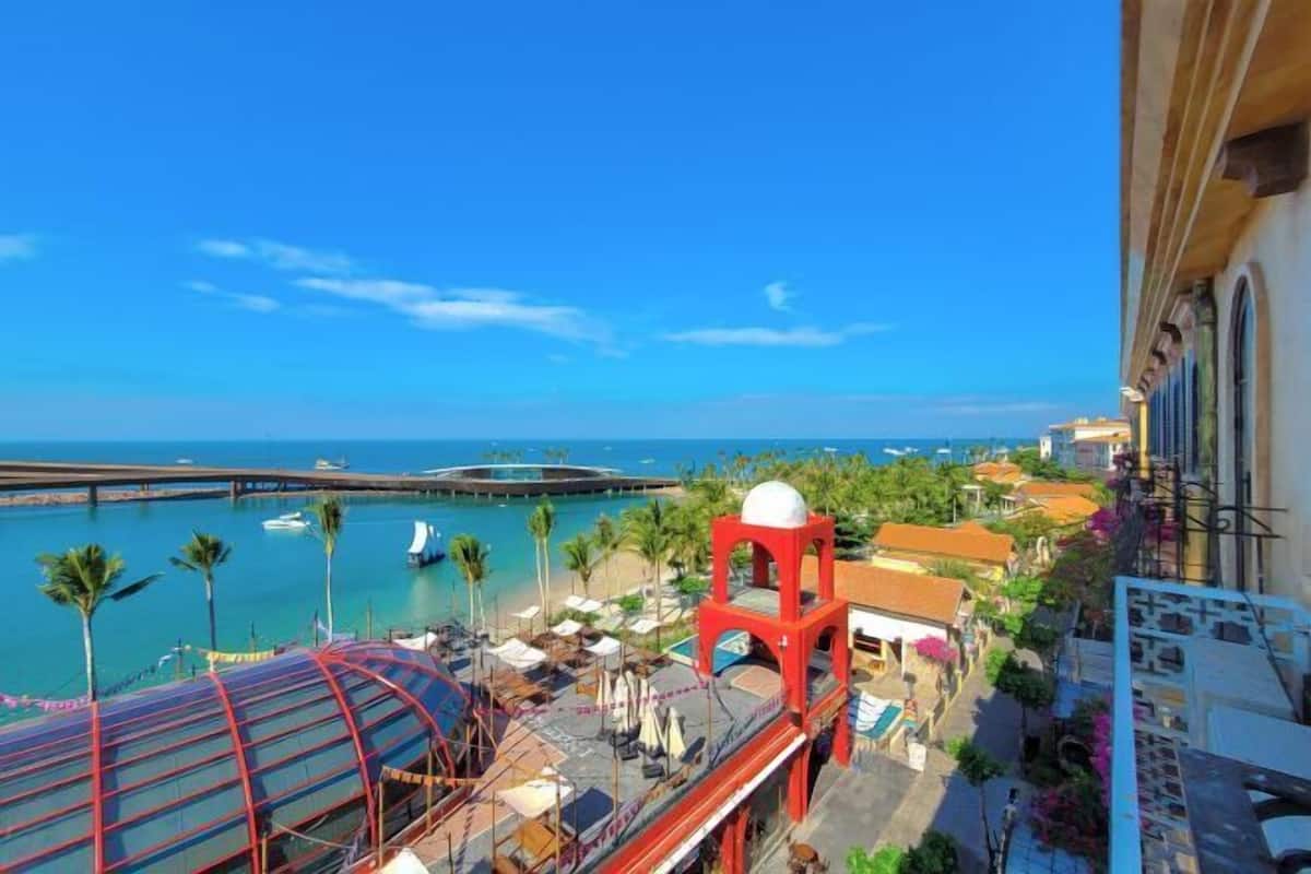 A coastal hotel with a view of the sea, a red tower, and a covered walkway.