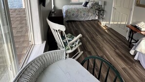Une chambre avec un lit, une chaise, une table et une fenêtre donnant sur une plage.