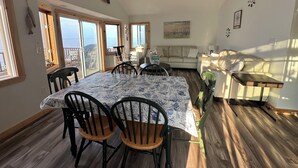 Une pièce spacieuse comprenant une table à manger, des chaises, un canapé et un ventilateur de plafond.