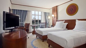 Une chambre d’hôtel avec deux lits, une télévision, un bureau et une vue sur l’extérieur.