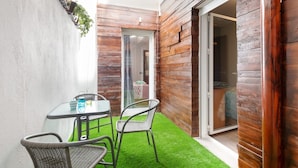 A small patio with a glass table and wicker chairs, a wooden wall, and a sliding glass door leading to an interior room. - Burriana Centro (Burriana)