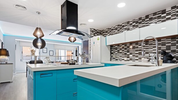 A modern kitchen with a central island, teal cabinetry, and a black and white patterned backsplash. - Burriana Centro (Burriana)