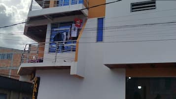 Un edificio de varios pisos con balcones, una tienda de ropa y una motocicleta estacionada.