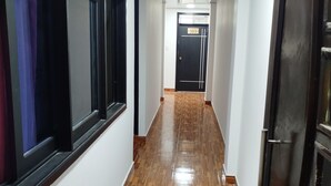 A hallway with wooden flooring, white walls, and a black door with a number sign. - Hotel Ancestral Rojas coffee (San José de Isnos)