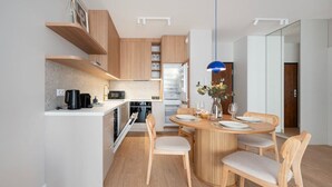 Een moderne keuken met houten kastjes, een inbouwoven en een eetgedeelte met een ronde tafel en stoelen.