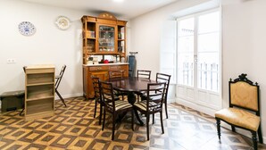Een eetruimte met een ronde tafel, zes stoelen, een houten kast met glazen deuren en vloertegels met een patroon.
