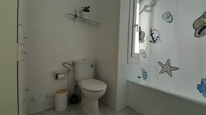 A small bathroom with a toilet, a trash can, and a shelf above the toilet. - Atico con Terraza en Vilagarcia de Arousa (Vilagarcia de Arousa)