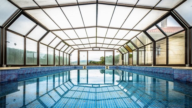 An indoor swimming pool with clear glass walls and a tiled floor. - Casa de Lujo con Pisicina y Jardin en el Rural (Meis)
