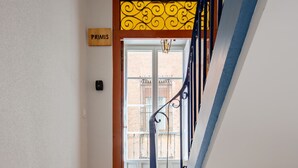A wooden staircase with blue handrails leading to a door with a yellow decorative panel. - Primis - CatedralHomes (Avila)