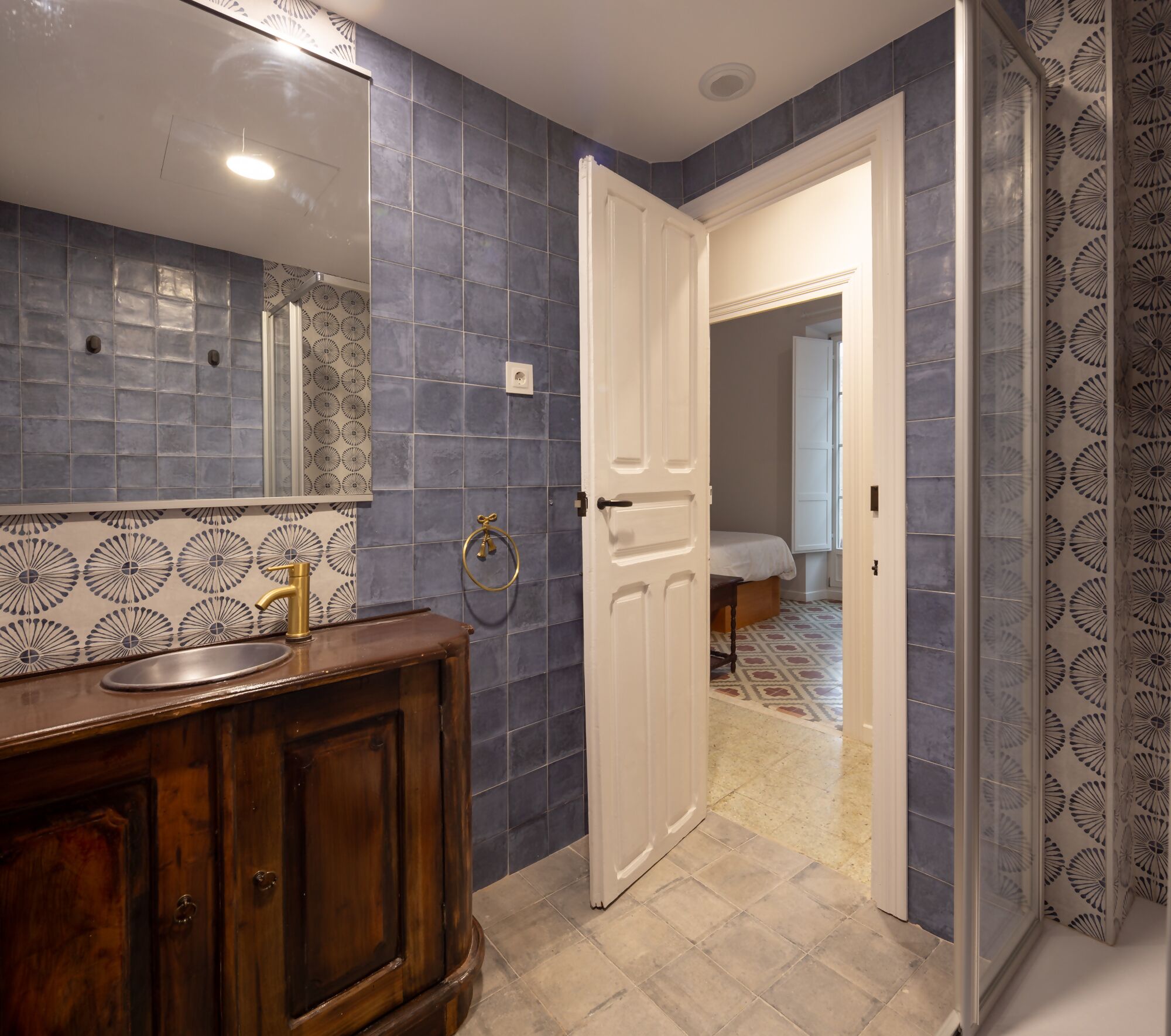 A bathroom with a sink, mirror, and patterned tiles.