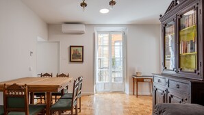 A dining area with a wooden table and chairs, a cabinet with glass doors, and a view through a door to an outdoor balcony. - Primis - CatedralHomes (Avila)