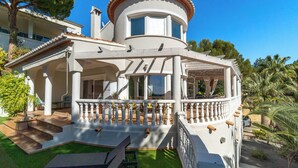 Una villa blanca con una torre circular, un porche cubierto y una piscina pequeña.