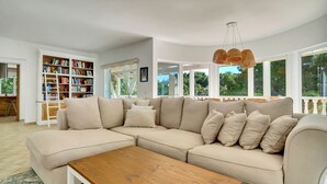 Una sala moderna con un sofá seccional color beige, una mesa de centro de madera y una amplia estantería.