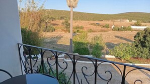 A balcony with a table and chairs, overlooking a rural landscape with hills and sparse vegetation. - Herdade do Castanheiro nur Wenige Min. von Lagos in Traumhafter Ruhiger Lage (Bensafrim/ Lagos)